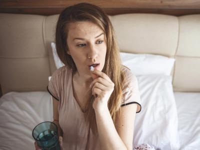 Young woman taking a white pill