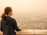 Woman with N95 overlooking polluted city