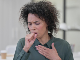 Woman coughing with hand on chest