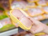 Hand holding packaged chicken in grocery store