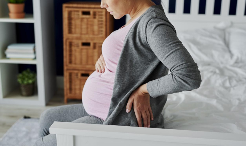 Pregnant woman sitting on bed