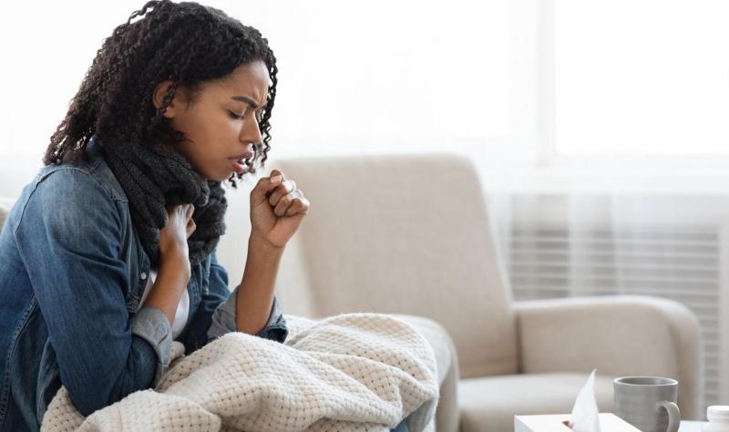 Young woman coughing on couch