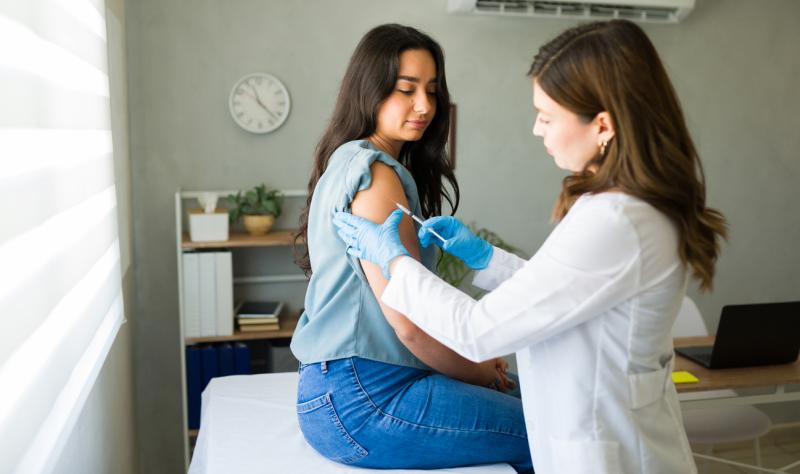 Young woman receiving a flu shot from female doctor