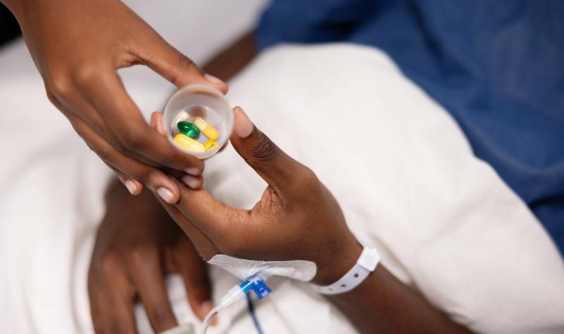 Nurse handing hospital patient a cup of pills