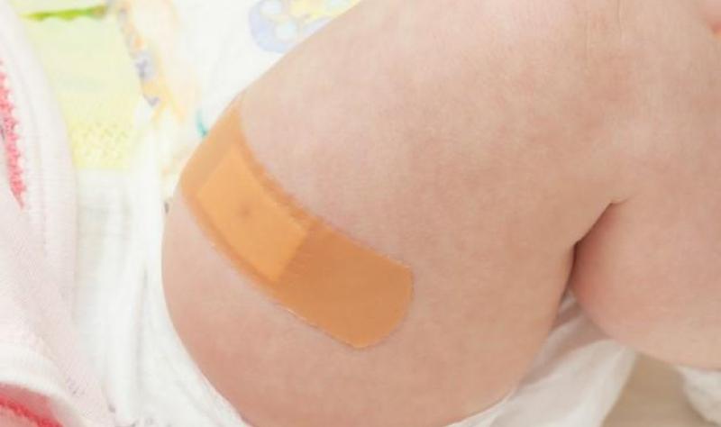 Vaccinated infant with bandage on thigh