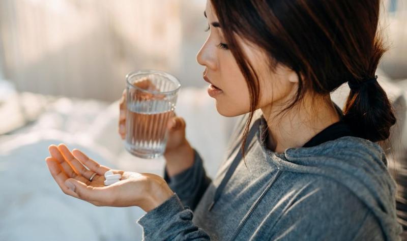 Woman taking white tablets