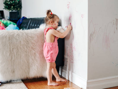 Toddler girl drawing on wall