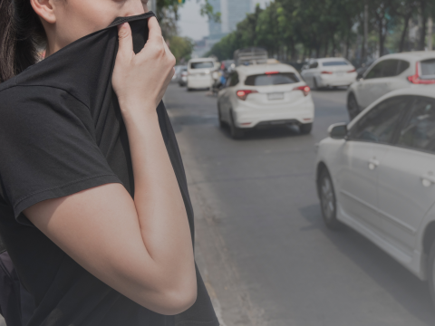 Woman holding up cloth to face to avoid air pollution from cars
