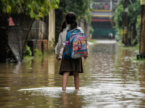 Girl walking in floodwaters in India