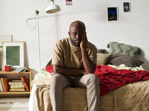 Fatigued man sitting on bed