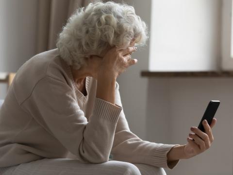 Frustrated elderly woman on smartphone