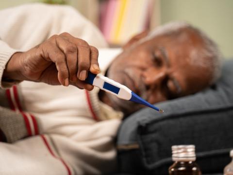 Older man in bed checking temp