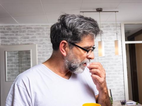 Older man taking white pill