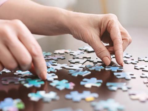 Pair of hands working jigsaw puzzle