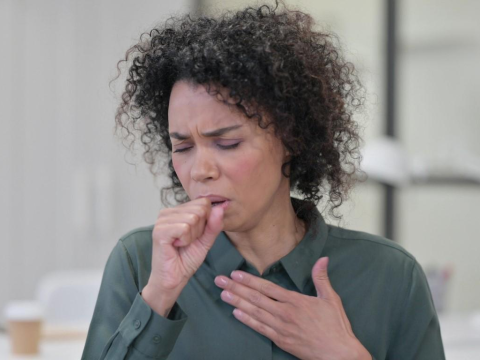 Woman coughing with hand on chest