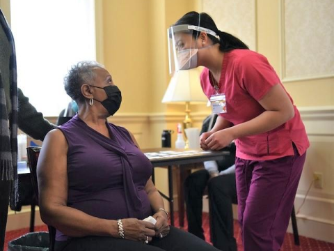 Young woman vaccinating older woman