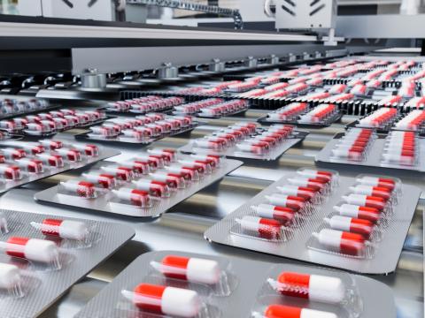 Red and white capsules in blister packs on production line