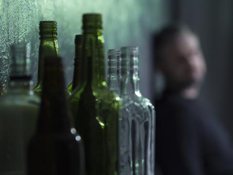 Alcoholic with empty bottle in foreground