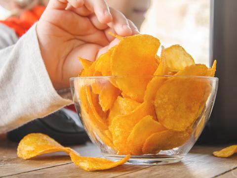 Child using computer while eating potato chips