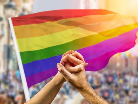 Clasped hands in front of pride flag