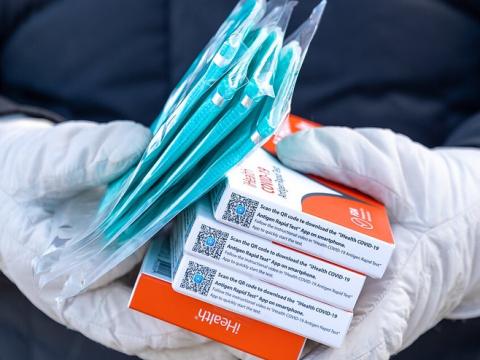 COVID masks and tests in gloved hands
