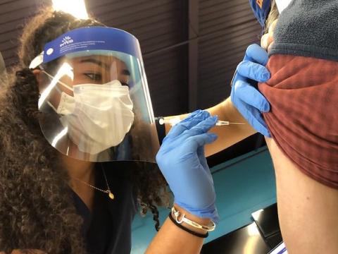 COVID vaccinator wearing mask, face shield
