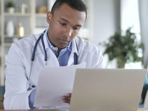 Doctor taking notes at laptop