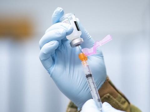 Drawing COVID vaccine from vial into syringe