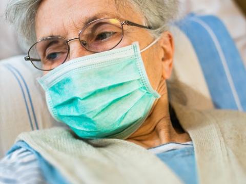 Elderly woman in bed wearing a mask