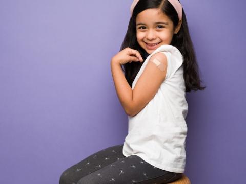 Girl displaying vaccine bandage on arm