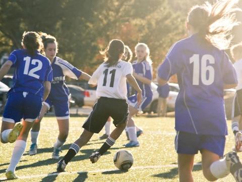 Girls playing soccer on sunny field
