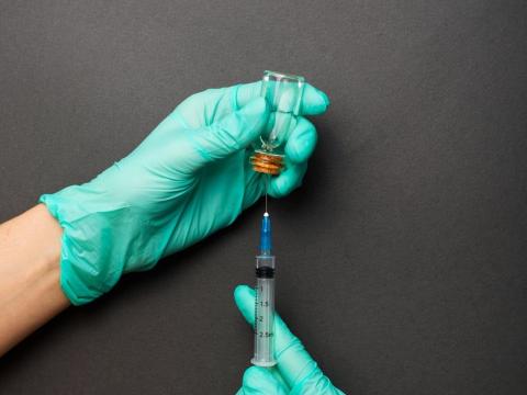 Gloved hands preparing vaccine in syringe