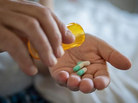 Green and white capsules in person's hand