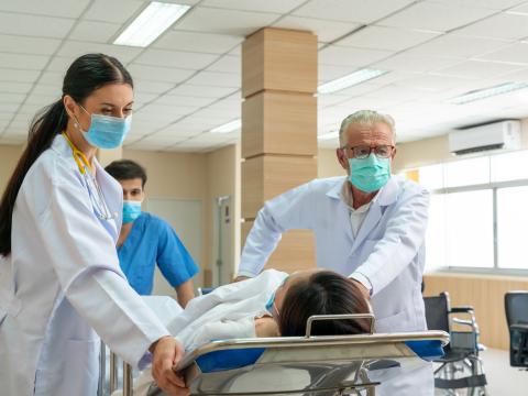 Healthcare workers rush in a patient on a hospital bed.