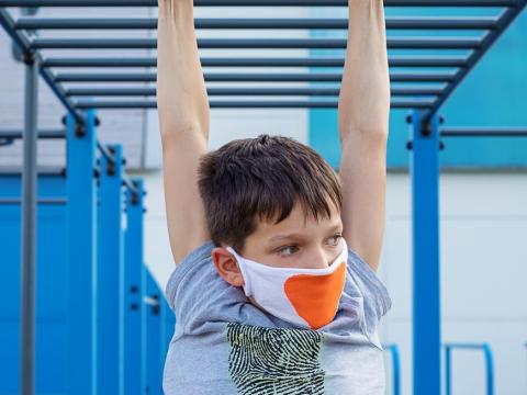 Boy wearing mask and hanging on rings