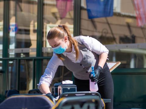 Lithuanian waitress disinfecting tables outdoors