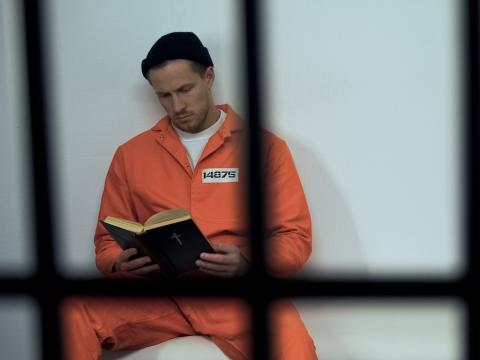 Man reading in prison cell