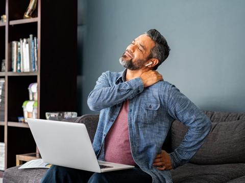 Man at laptop experiencing neck, shoulder pain