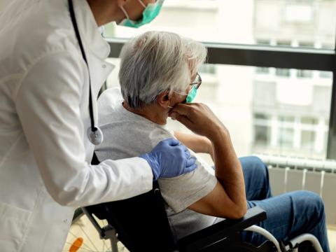 Nursing home patient in wheelchair with caregiver