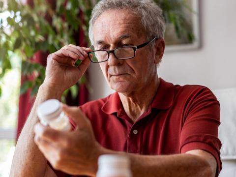 Older man reading pill bottle instructions