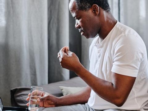 Older man taking pills with water glass