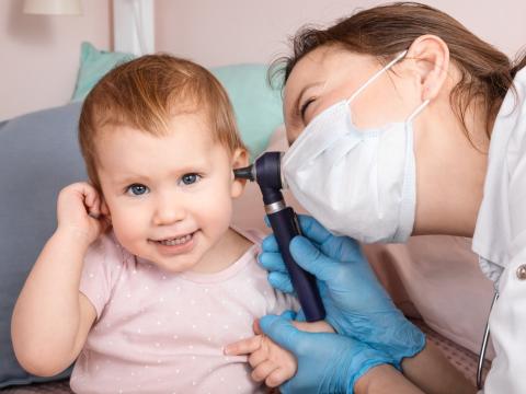 Pediatrician examining little girl's ears
