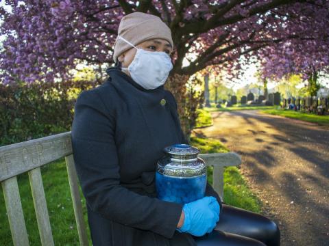 Woman wearing mask and holding urn in cemetary