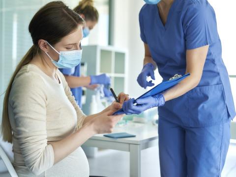 Pregnant woman signing vaccine paperwork