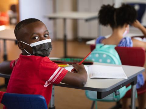 Young student wearing mask at desk