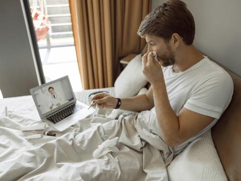 Sick man in bed telehealth consult
