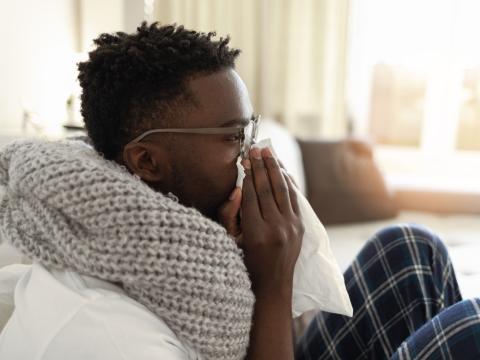 Sick man on couch blowing nose