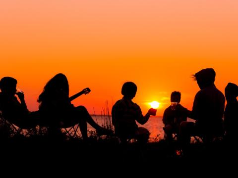 Teens at camp at sunset in silhouette