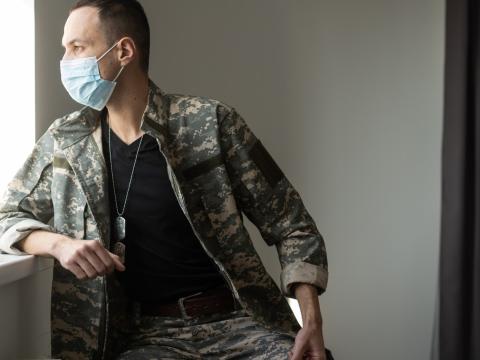 Soldier wearing mask and looking out window