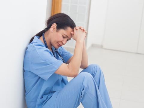 Stressed-out nurse sitting on floor